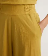 Pantalón harem color mostaza, con cintura elástica ancha, pliegues delanteros y horizontales, barra ajustada con elástico y pliegues.