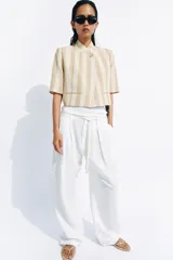 Blazer cropped de manga corta de Zara Woman Collection, confeccionado en hilatura con algodón, con diseño a rayas verticales en tonos beige y blanco. Cuenta con cuello subido, bolsillos de vivo en el delantero, forro interior y cierre frontal con botón.