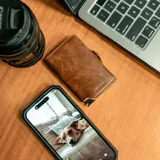 Billetera tipo tarjetero de cuero negro con caja de aluminio interna y sistema de deslizamiento para tarjetas. Cuenta con cierre mediante broche a presión.