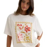 Remera de corte oversized color blanco, con cuello redondo y mangas cortas. Presenta un estampado frontal de flores en tonos cálidos, enmarcado por un diseño de círculos concéntricos.