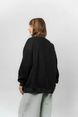 Buzo oversize de cuello redondo, confeccionado en algodón suave con interior frizado. Presenta un diseño de líneas simples, corte relajado y mangas largas con puños ajustados.