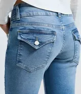 Pantalón de jean modelo boot cut en color azul claro, con cintura baja, cierre frontal con doble botón y cremallera, bolsillos funcionales y trabillas para cinturón.