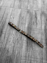 Cinto fino con estampado animal print y ojalillos metálicos plateados.