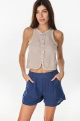 Top musculosa de lino en color beige, sin mangas, con cierre frontal de botones de nácar y escote redondo.