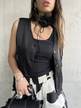 Chaleco sastrero negro con botones, de corte corto y moderno.