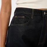 Jean de corte regular y tiro alto, confeccionado en denim azul oscuro. Presenta un diseño de pierna recta con un dobladillo ancho y llamativo en la parte inferior que deja ver el revés de la tela.