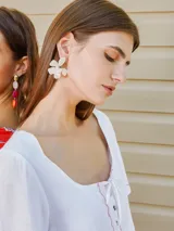 Aros con diseño de flor de pétalos blancos y centro con textura, estilo colgante.