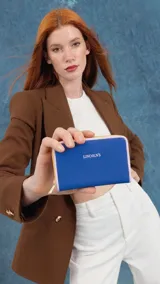 Billetera mediana de diseño rectangular, color negro con bordes en tono suela. Cuenta con cierre perimetral metálico y logo de la marca estampado en el frente.