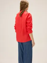 Camisa de lino color crudo, con cuello mao y cierre frontal con botones. Cuenta con detalles de alforzas verticales y diseño bordado floral en el frente, además de mangas 3/4 con volumen y puños elásticos.