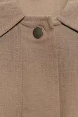 Chaqueta color beige con cuello solapa, manga larga remangada con trabilla y botón, y bolsillos de plastrón en el delantero. Cierre frontal con botones.
