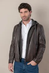 Campera de cuero negro con capucha gris desmontable, cierre frontal, bolsillos con cierre y detalles de hebillas en el cuello y la cintura.