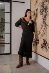 Vestido corto negro de tejido de punto con cuello en V, mangas 3/4, flecos en el ruedo y apliques de cuero en escote y hombros.