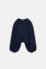 Top azul marino de tejido fluido con cuello redondo y manga larga abullonada con aberturas. Presenta una abertura en la espalda con tira del mismo tejido y cierre de ganchos metálicos.