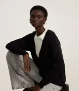 Cardigan corto de punto color marrón, con cuello en V, manga larga y cierre frontal con botones. Presenta puños y bajo acanalados.