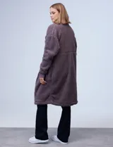 Campera larga de sherpa color negro, con cierre frontal y bolsillos laterales.