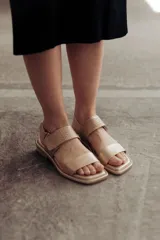 Sandalia Roma de cuero dorado, con tiras anchas, una lisa en la puntera y otra con textura reptil en el empeine, y tira ajustable al talón con hebilla. Suela plana y cómoda.
