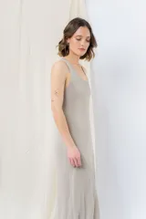 Vestido midi de tejido tipo seda con caída fluida, escote redondo y sin mangas. Presenta un diseño minimalista con detalle de flecos en el ruedo.