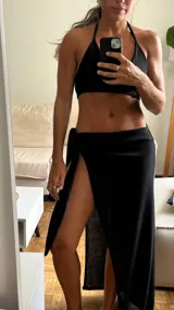 Pareo negro de tejido de punto con abertura lateral y ajuste con lazo.