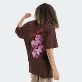 Remera blanca de corte oversized, con cuello redondo y mangas cortas. Presenta un pequeño estampado en el pecho con el logo de la marca Reef en color rojo y detalles de estrellas.