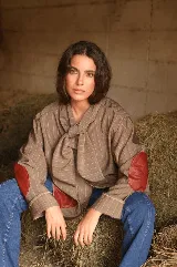 Blazer de corte oversize confeccionado en tela casimir a rayas, con cuello tipo lazo y parches de cuero en los codos y bolsillos frontales.