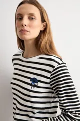 Remera rayada de manga larga en color blanco y negro, con cuello redondo y detalle de bordado floral en el pecho.