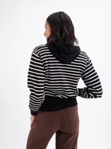 Campera de tejido de punto con capucha, diseño a rayas horizontales en blanco y negro, con puños y cintura en tejido liso negro.