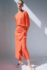 Vestido midi color naranja de la colección ZW de Zara, con cuello redondo, manga corta y detalle de tejido drapeado con volados en el delantero. Cuenta con cierre en la espalda con abertura y botón.