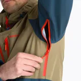 Campera impermeable tipo hardshell de la marca Merrell, con diseño bicolor en tonos arena y azul oscuro. Cuenta con capucha ajustable, cierre frontal y bolsillos en el pecho con cremalleras impermeables en color naranja vibrante, ventilación en axilas y puños ajustables.