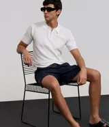 Remera polo slim de Marfinno confeccionada en viscosa texturizada de color blanco, con cuello polo y cierre frontal de cremallera corta, de manga corta.