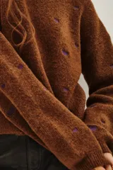 Sweater de punto color marrón con diseño de pequeños corazones bordados en color violeta, de corte holgado y manga larga.