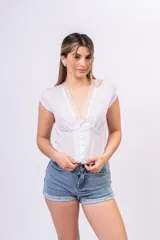 Blusa de lino liviano color blanco con textura plumeti, escote en V con detalle de encaje, botones frontales y mangas cortas.