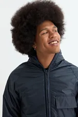 Campera de nylon color azul oscuro, con cierre frontal, capucha y bolsillos laterales con solapa. Presenta puños elásticos acanalados.