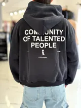 Hoodie de corte boxy fit en color negro, con capucha y estampa en la espalda con texto en blanco que dice 'Community of talented people' junto con un pequeño logotipo y el texto 'creative studio'.
