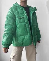 Campera puffer verde con capucha, cierre frontal con cremallera y bolsillos con solapa.