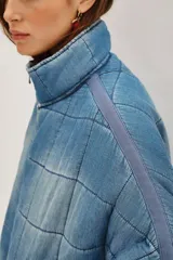 Campera acolchada de corte holgado con diseño de costuras cuadradas, cierre frontal con cremallera y cuello alto. Presenta un acabado lavado en tonos gris y negro.