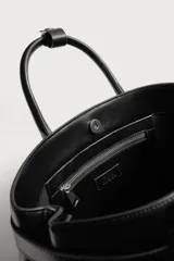 Bolso de mano estructurado en color negro, con diseño minimalista y detalle de cinturón decorativo en la parte superior. Cuenta con doble asa de mano y cierre magnético.