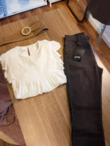 Jeans de corte flare color marrón oscuro, confeccionados en denim, con tiro medio, bolsillos clásicos y detalle de dobladillo deshilachado con pequeña abertura lateral en los tobillos.