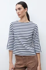Remera de manga tres cuartos con diseño a rayas horizontales en azul marino y blanco. Presenta un detalle de volados laterales en las mangas y cuello redondo.