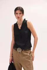 Top sin mangas color blanco con escote en V y volados en el cuello y la botonera delantera.