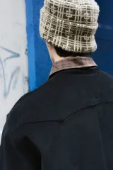 Sobrecamisa negra de corte clásico con cuello camisero en contraste color marrón a cuadros. Presenta cierre frontal con botones, dos bolsillos frontales tipo parche y una etiqueta decorativa con el logo de la marca en el pecho.