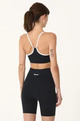 Top deportivo negro con breteles blancos y logo Basset estampado en el frente.