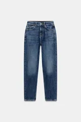 Jeans mom fit de tiro alto y largo tobillero, confeccionados en denim azul con efecto deslavado. Presentan diseño de cinco bolsillos, trabillas para cinturón y cierre frontal con cremallera y botón metálico.