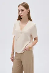 Blusa marrón de manga corta con cuello en V y cierre frontal cruzado con tres botones.