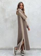 Vestido largo de punto en color gris oscuro y beige, con diseño de paneles laterales en contraste, mangas largas abullonadas con textura perforada y tajos laterales en el ruedo.