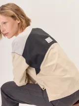 Buzo de cuello redondo con diseño de bloques de color y texturas. Presenta una combinación de paneles en color beige, gris con trama de espiga y una sección central oscura con diseño de cuadrícula. Confeccionado en algodón con detalles en lana.