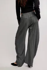 Pantalón de vestir gris con rayas finas, de silueta barrel, tiro medio, con cierre de cremallera y botón, y bolsillos.