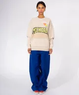 Buzo de algodón y poliéster, color azul oscuro con efecto desgastado/tie-dye. Presenta un gran estampado frontal con la palabra "MICHIGAN" en amarillo con borde negro, un corazón naranja y apliques de pines decorativos en la parte superior. Tiene cuello redondo con terminación deshilachada y bolsillo canguro frontal.