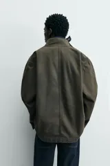 Parka de algodón con acabado lavado, color verde oscuro, de corte relajado. Presenta cuello subido, cierre frontal oculto por solapa con botones a presión, bolsillos de vivo en el pecho y bolsillos plastrón en la cadera.