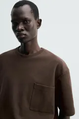Remera de corte relajado confeccionada en tejido compacto de mezcla de algodón con elasticidad. Presenta cuello redondo, manga corta y un bolsillo frontal de plastrón.