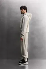 Sudadera con capucha color gris claro, de corte holgado, con bolsillo tipo canguro y cordones ajustables.